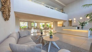 Eine moderne Hotelhalle mit Empfangstresen, Sitzgelegenheiten und großen Fenstern.