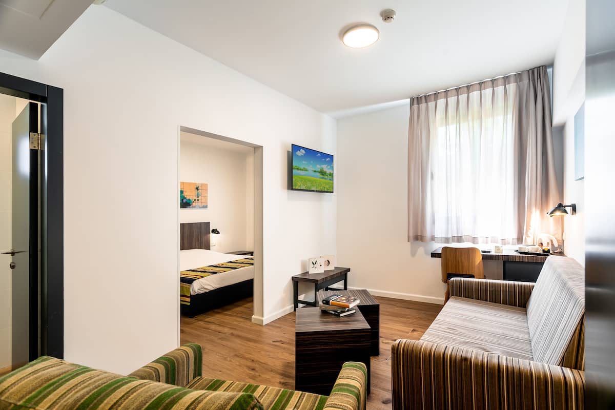 Une chambre d’hôtel moderne équipée d’un lit, d’un canapé, d’une petite table et d’un bureau.