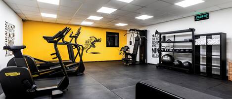 Un gimnasio con cintas de correr, bicicletas estáticas y equipo de levantamiento de pesas.
