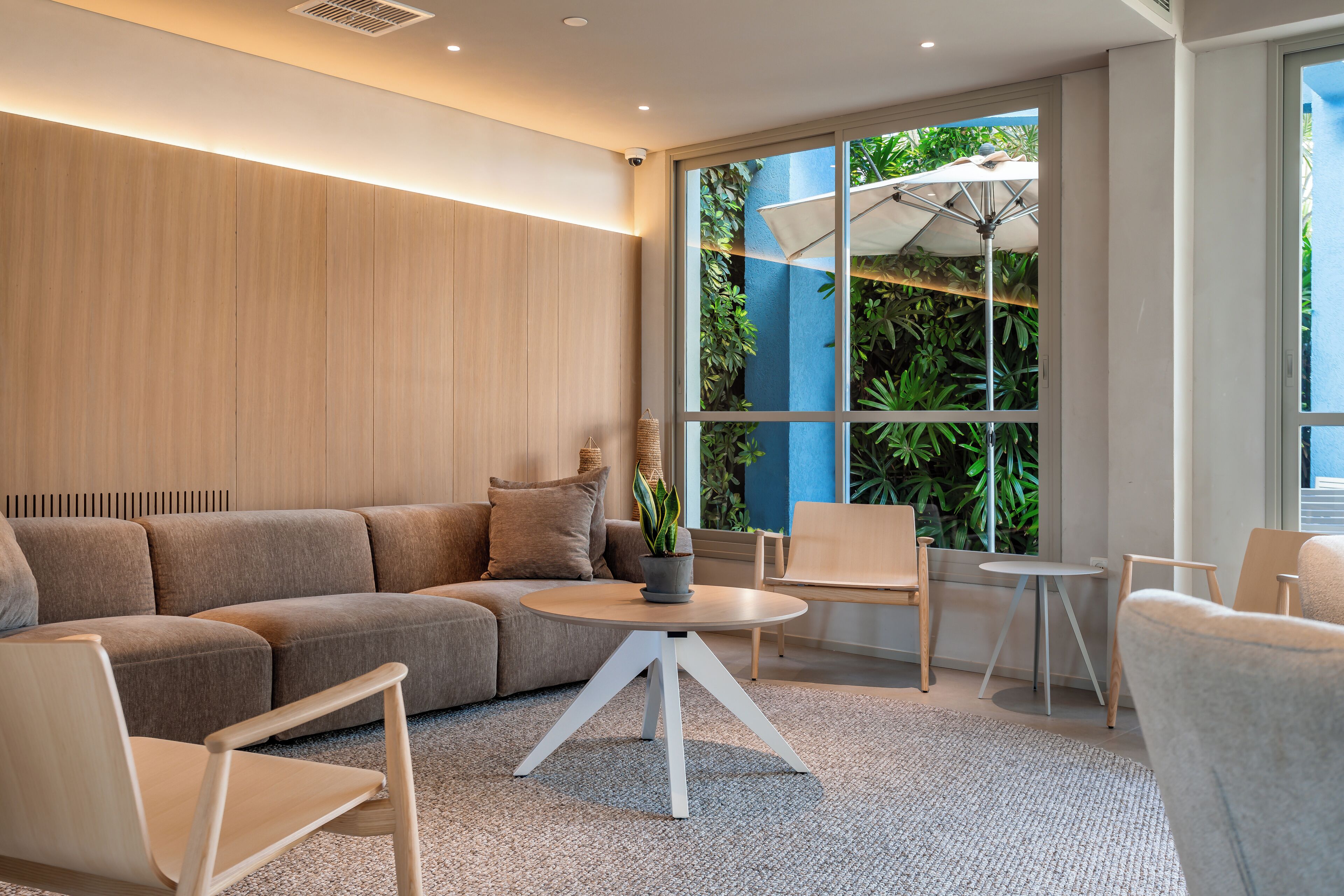 A modern living room with a sectional sofa, a round coffee table, and a large window with a view of greenery.