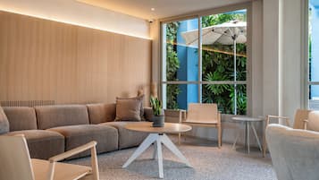 A modern living room with a sectional sofa, a round coffee table, and a large window with a view of greenery.