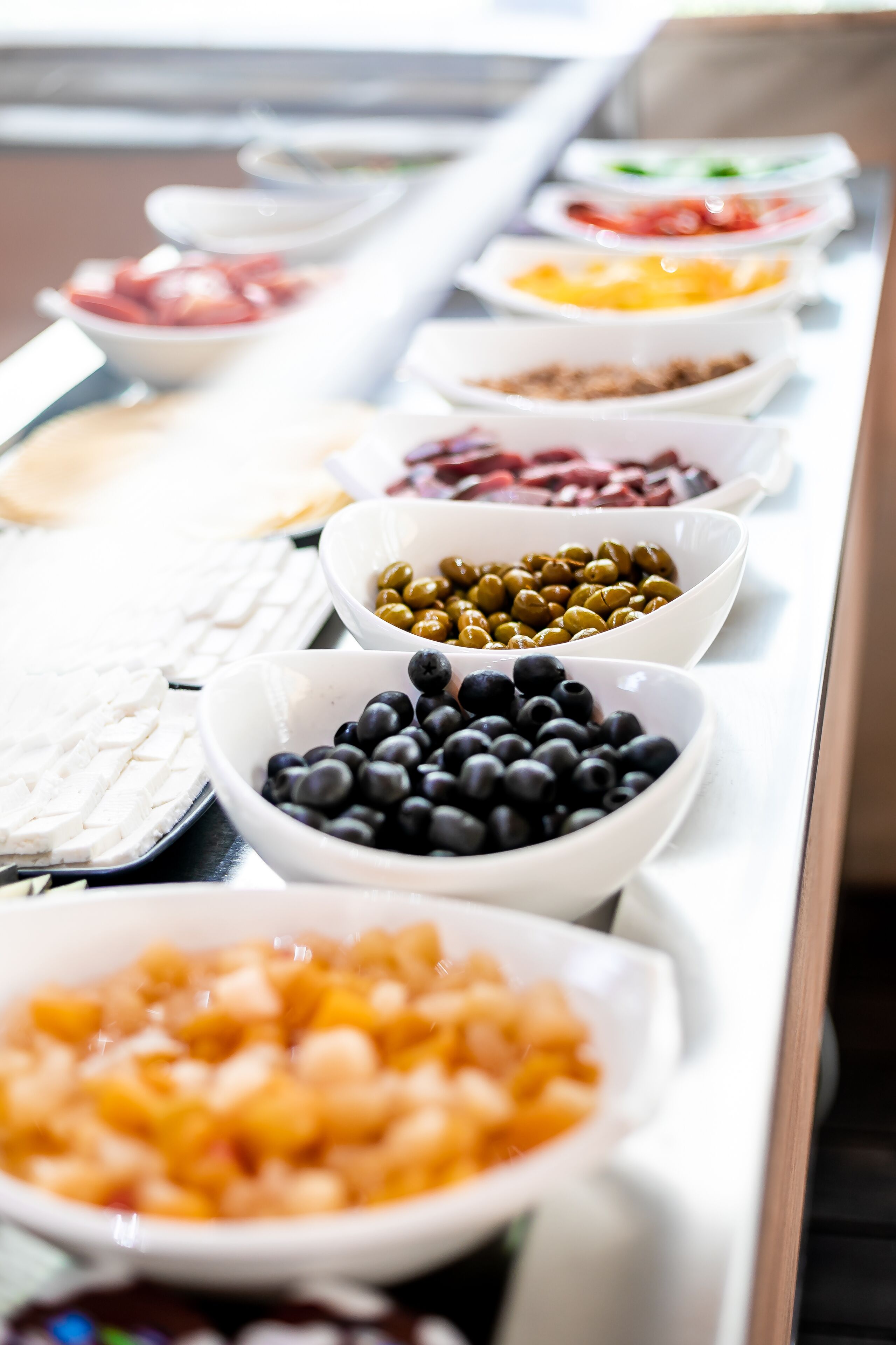 A buffet line with various food options including olives, blueberries, and other dishes.