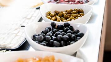 Un buffet proposant une variété de plats, notamment des olives, des myrtilles et d’autres mets.