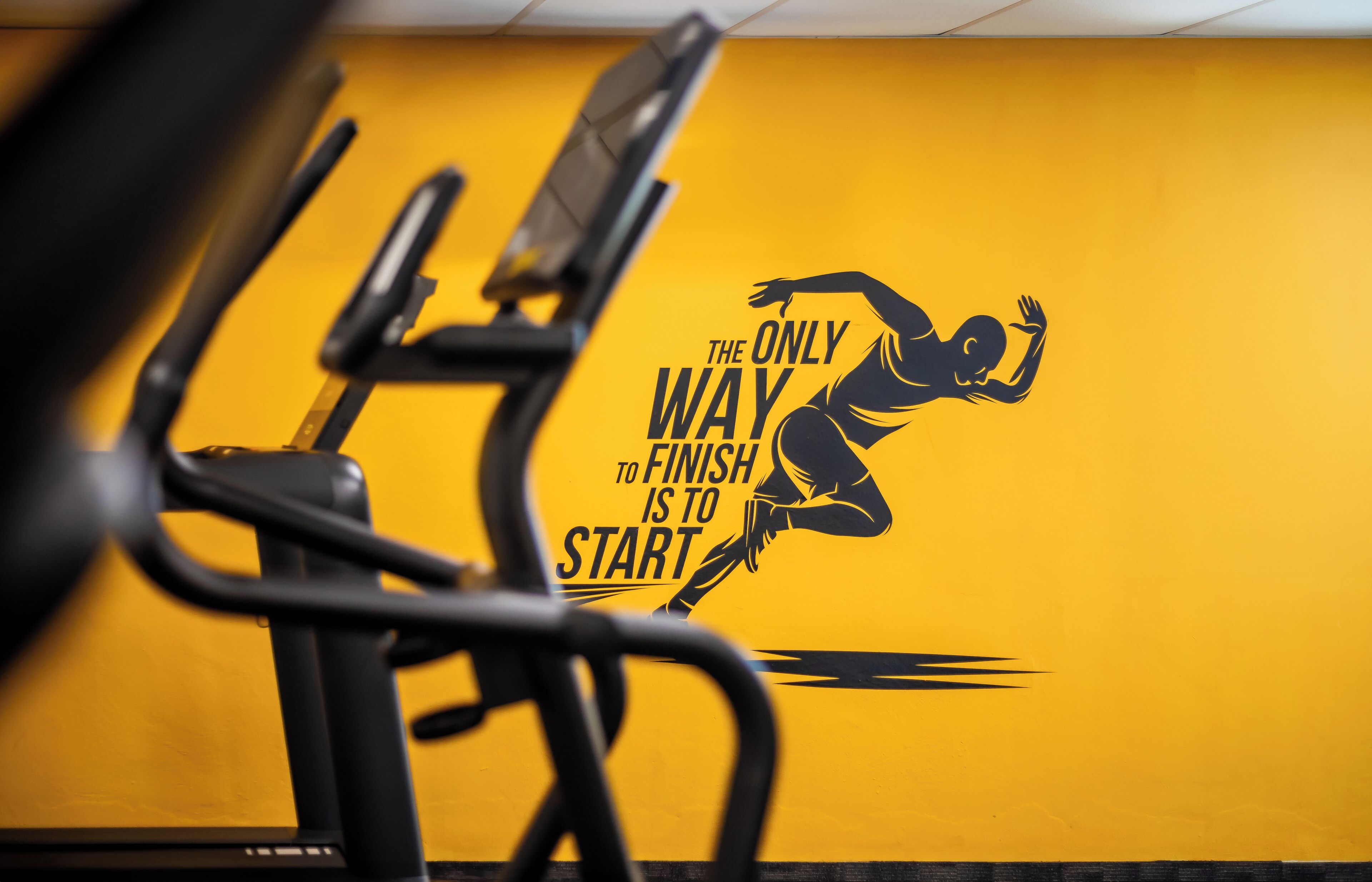 Un mur orné d’une citation inspirante et de la silhouette d’une personne en train de courir.