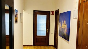 A hallway with wooden flooring, a door with a frosted glass panel, and a painting of a building on the wall. - CH Arriaza II (Madrid)