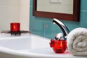 Un lavabo de salle de bain avec une serviette blanche et une bougie rouge.