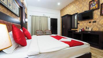 A hotel room with a large bed, a TV, a desk, and a wardrobe.