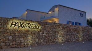 A modern building with a stone wall and a sign reading "PAXHOUSES". - Pax House 1 (Krk)