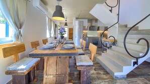 A dining area with a wooden table, benches, and a staircase with a metal handrail. - Pax House 1 (Krk)