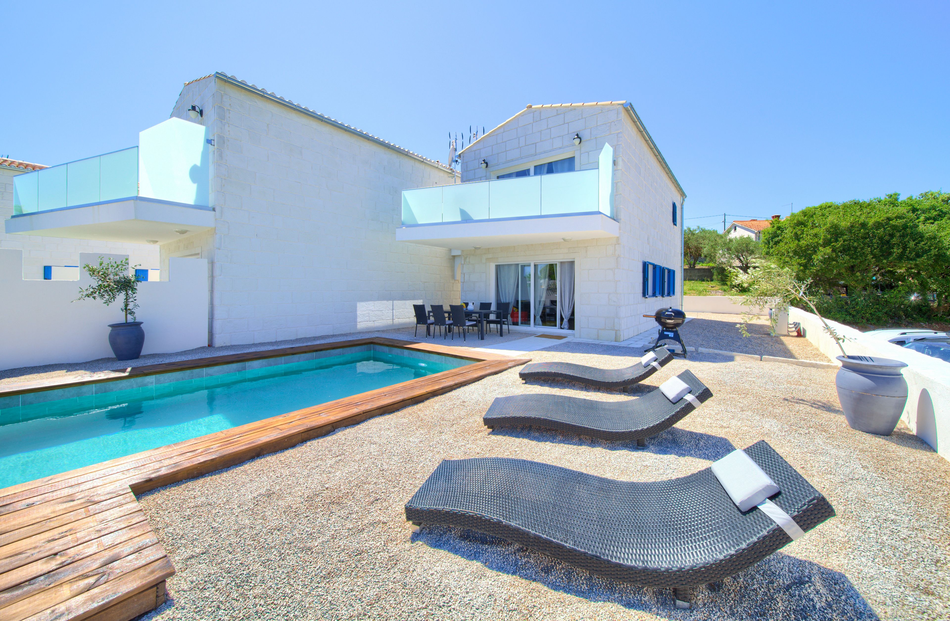 Una casa moderna con piscina, mobiliario exterior y jardín.