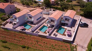 A large property with multiple buildings, each featuring a swimming pool and outdoor seating areas. - Pax House 2 (Krk)