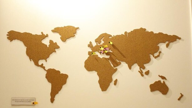 A cork map of the world with pins indicating locations.
