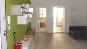 A spacious living room with a green accent wall, a wooden cabinet, and a red storage box.