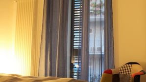 A bedroom with a bed, a chair, and a window with curtains.