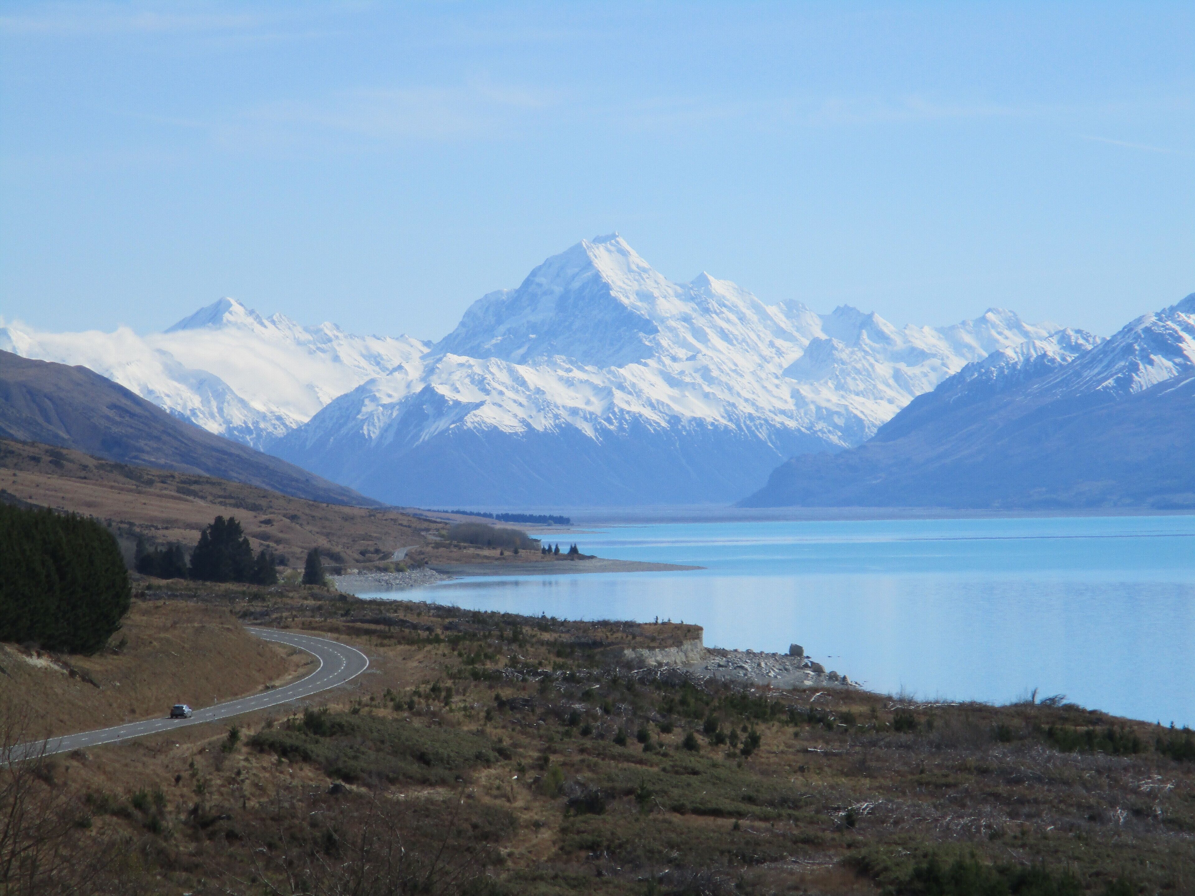 Paisagem montanhosa com um lago e uma estrada sinuosa.