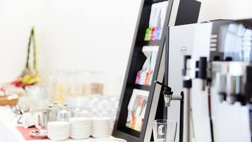 A buffet table with a beverage dispenser, stacked plates, and a glass display case.