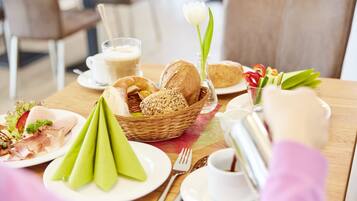A breakfast setting with bread, pastries, and a flower on a table.