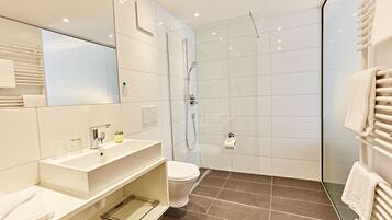 Un baño moderno con cabina de ducha de vidrio, un lavabo blanco y un inodoro.