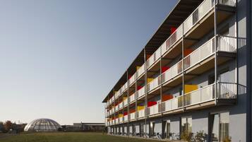 A modern multi-story building with balconies, a flat roof, and a clear sky.