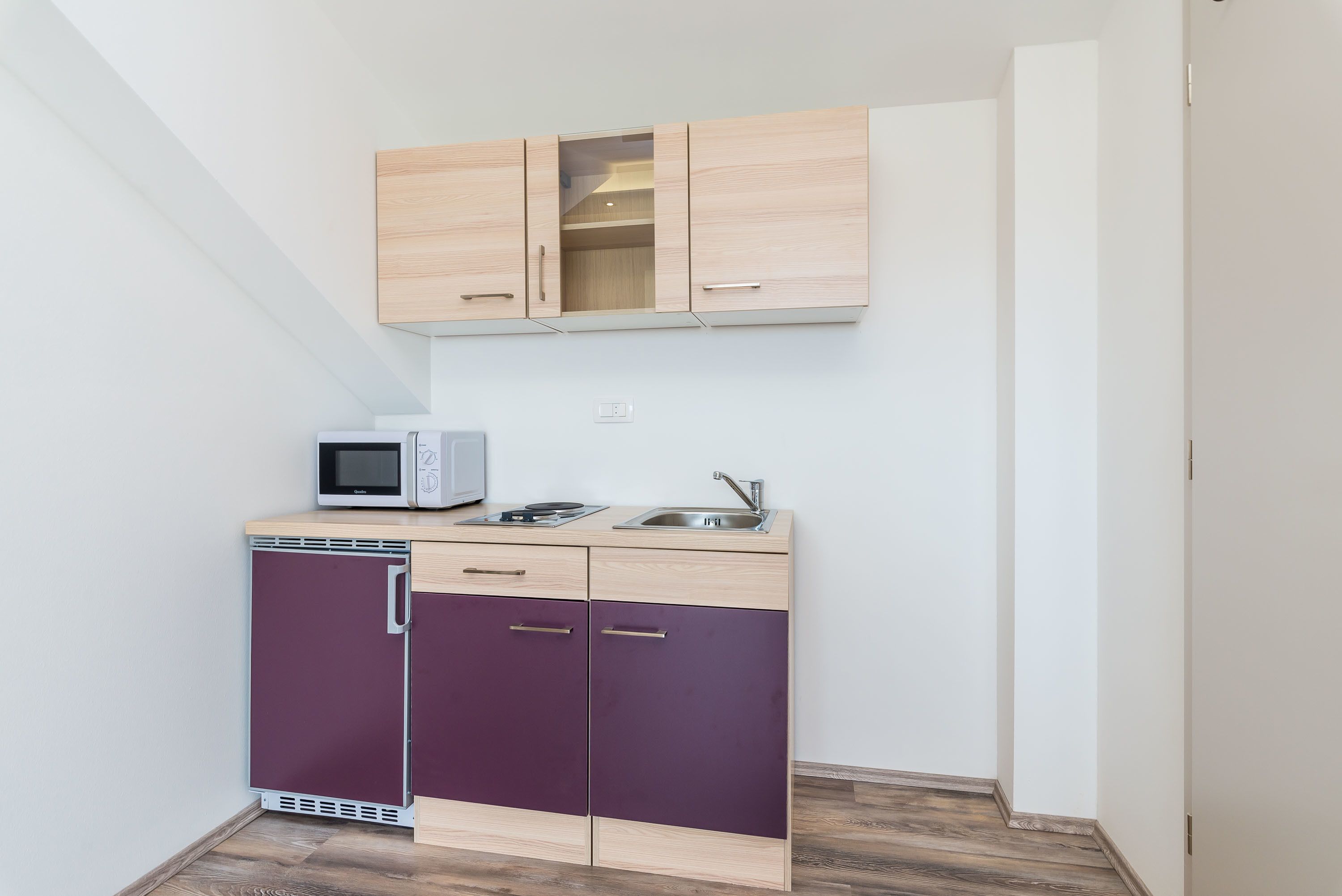 A compact kitchen with a microwave, sink, and dishwasher.