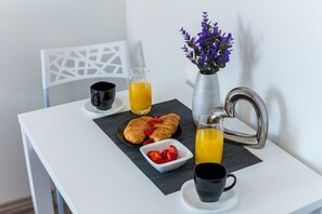 A breakfast setup with croissants, strawberries, orange juice, and a vase of purple flowers on a white table. - Bovolini's Place (Dubrovnik)