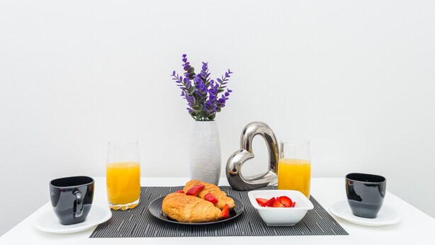 A breakfast setup with croissants, strawberries, and orange juice on a table. - Bovolini's Place (Dubrovnik)