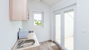 A modern kitchen with a built-in microwave, a sink, and a window overlooking a residential area. - Bovolini's Place (Dubrovnik)