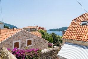 A stone building with a tiled roof, a small window, and a view of the sea.