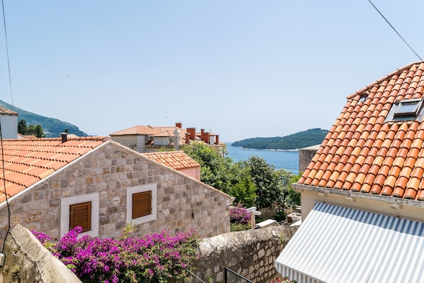 A stone building with a tiled roof, a small window, and a view of the sea.