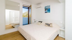 Un dormitorio con cama, mesita de noche, espejo y un cuadro en la pared.