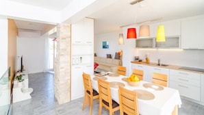 Una cocina moderna con armarios blancos, una mesa de comedor con sillas e iluminación colgante.