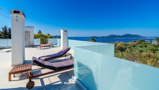 Terraza en la azotea con sillones de descanso y balaustrada de vidrio con vistas panorámicas.