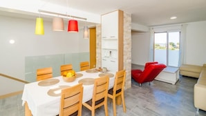 Un comedor moderno con una mesa blanca, sillas de madera y luces colgantes.
