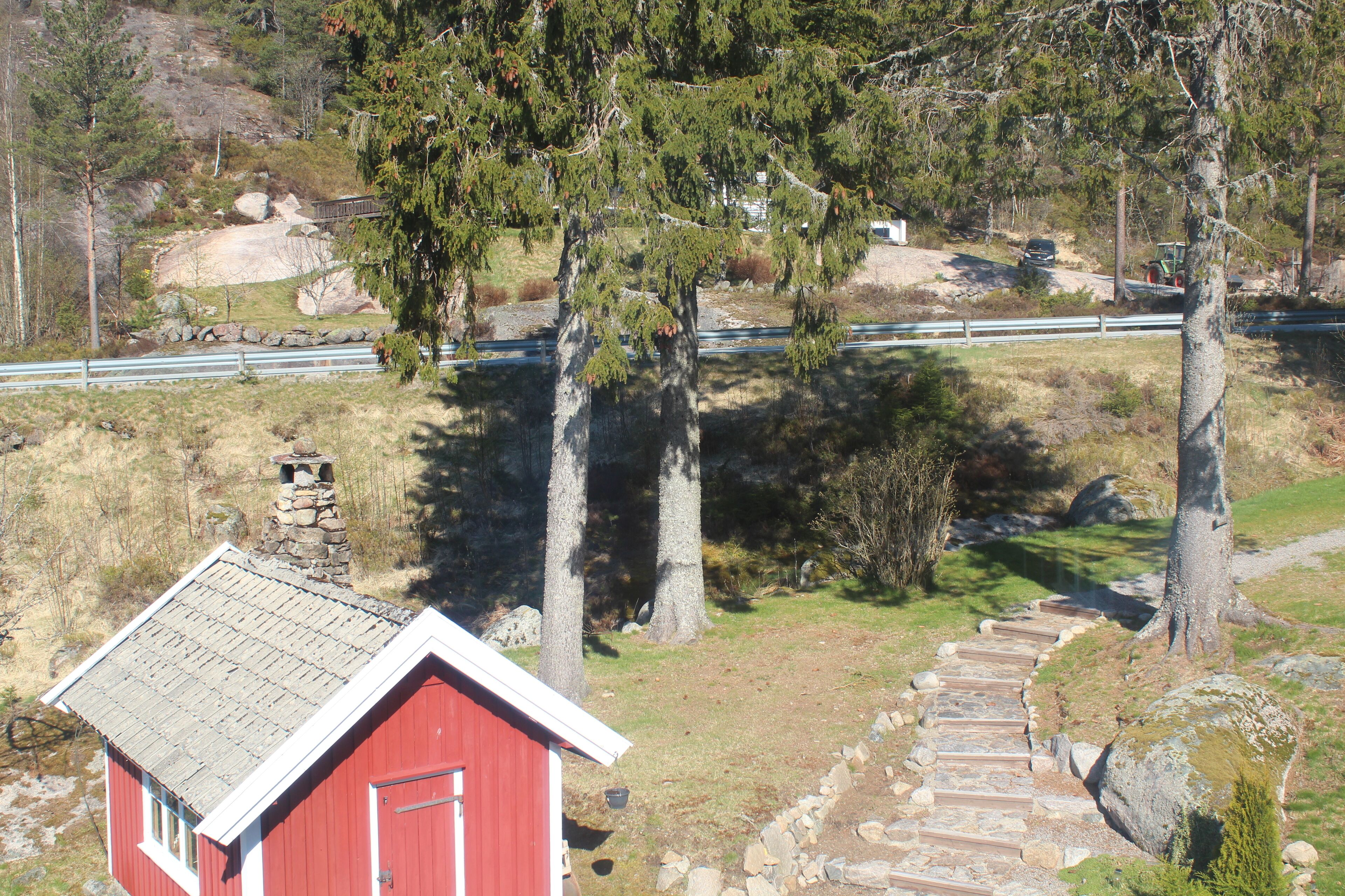 A red building with a stone chimney, a stone staircase, and a paved path.