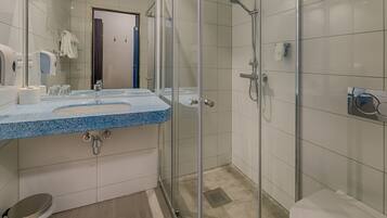 A modern bathroom with a glass-enclosed shower, a sink with a blue countertop, and a toilet.