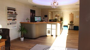 A reception area with a counter, a computer monitor, a potted plant, and a sign on the wall. - Hotell Eikerapen Gjestegard (Aseral)