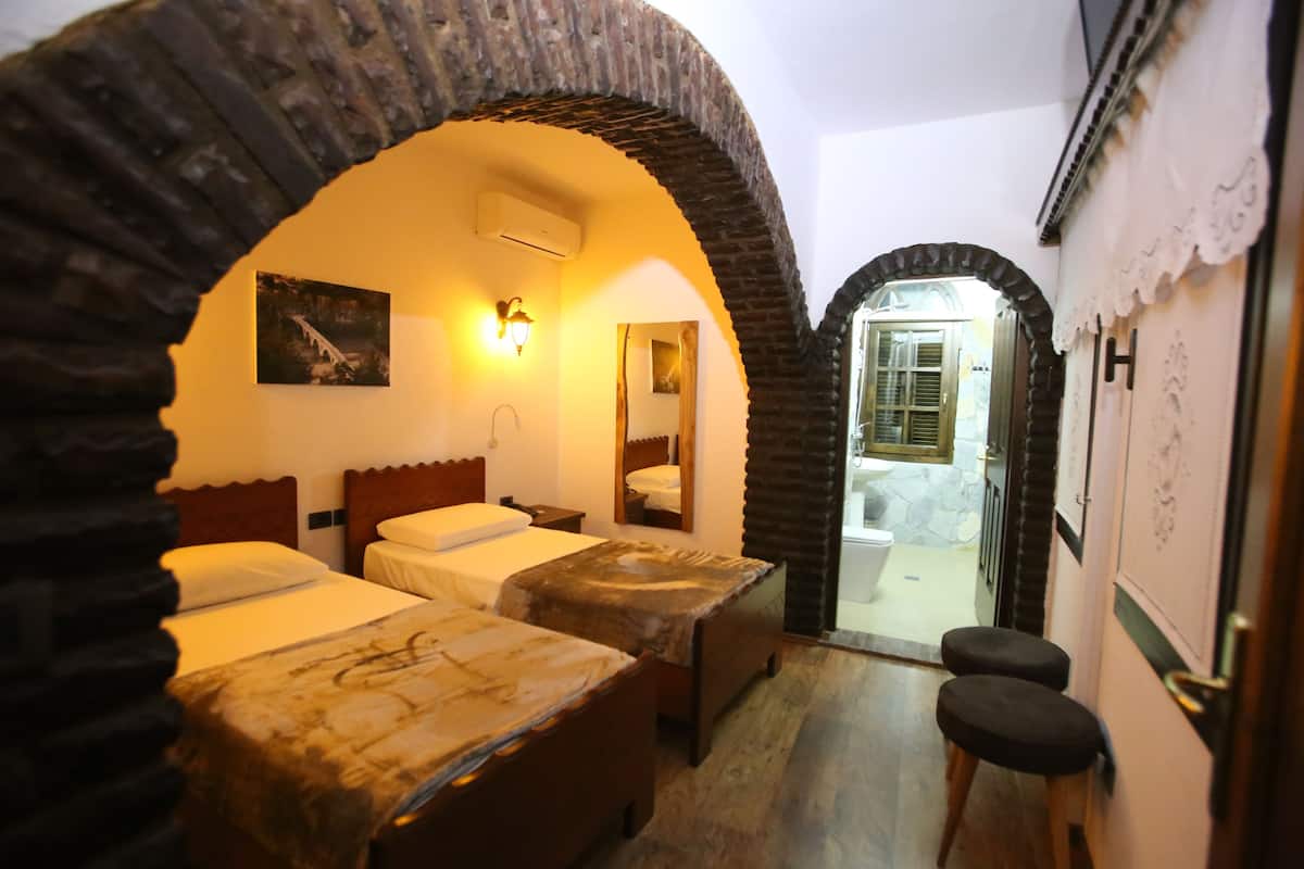 Una habitación con dos camas, un baño y un arco que conduce a otra habitación.