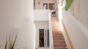 Una escalera conduce a un balcón en el segundo piso, con barandilla de madera.
