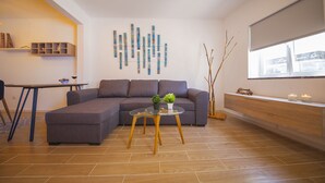 Una sala de estar moderna con un sofá seccional, una mesa de centro de vidrio, un aparador de madera y un elemento decorativo en la pared.