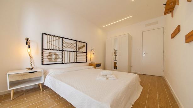 Un dormitorio con cama, mesita de noche, una obra de arte en la pared y armario.