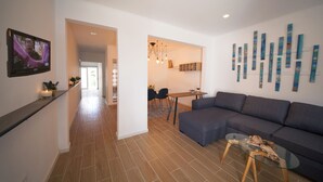 Una sala moderna con un sofá seccional, una mesa de centro de vidrio y un comedor con mesa y sillas.