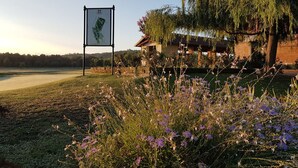 Un terrain de golf avec un panneau indicateur, un bâtiment doté d’un toit et un saule pleureur.
