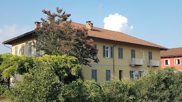 Un edificio a due piani con tetto in tegole rosse, numerose finestre e un camino ben visibile.