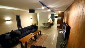Una sala moderna con un sofá modular, una mesa de centro de madera y un comedor con sillas.