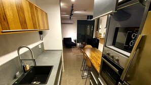 Una cocina moderna con horno empotrado, refrigerador de acero inoxidable y encimera de madera.