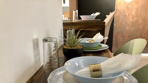 Una mesa de comedor con un tazón azul, un tarro de cristal y una planta en maceta.