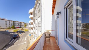 Un balcone con vista su una strada, un tavolo e una finestra.