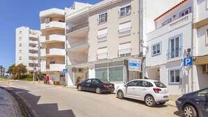 Un edificio a più piani con balconi, un'area di parcheggio e un attraversamento pedonale.