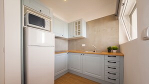 Una cucina compatta con mobili azzurri, un frigorifero bianco, un forno a microonde e un piano di lavoro in legno.