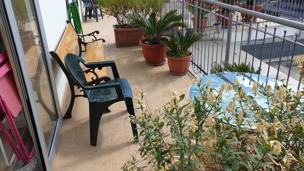 A balcony with a chair, potted plants, and a table. - B&B Casa Terry (Marcianise)